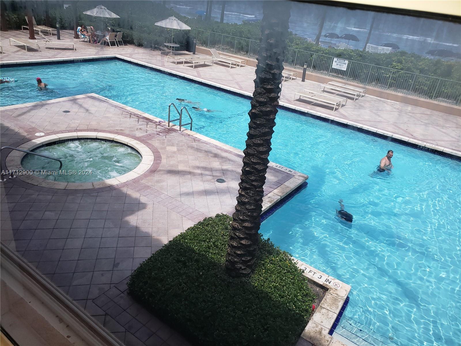 An elevated view of a swimming pool and hot tub surrounded by a tiled deck — 2080 S Ocean Dr # 311, Hallandale Beach FL 33009, HALLANDALE BEACH, FL