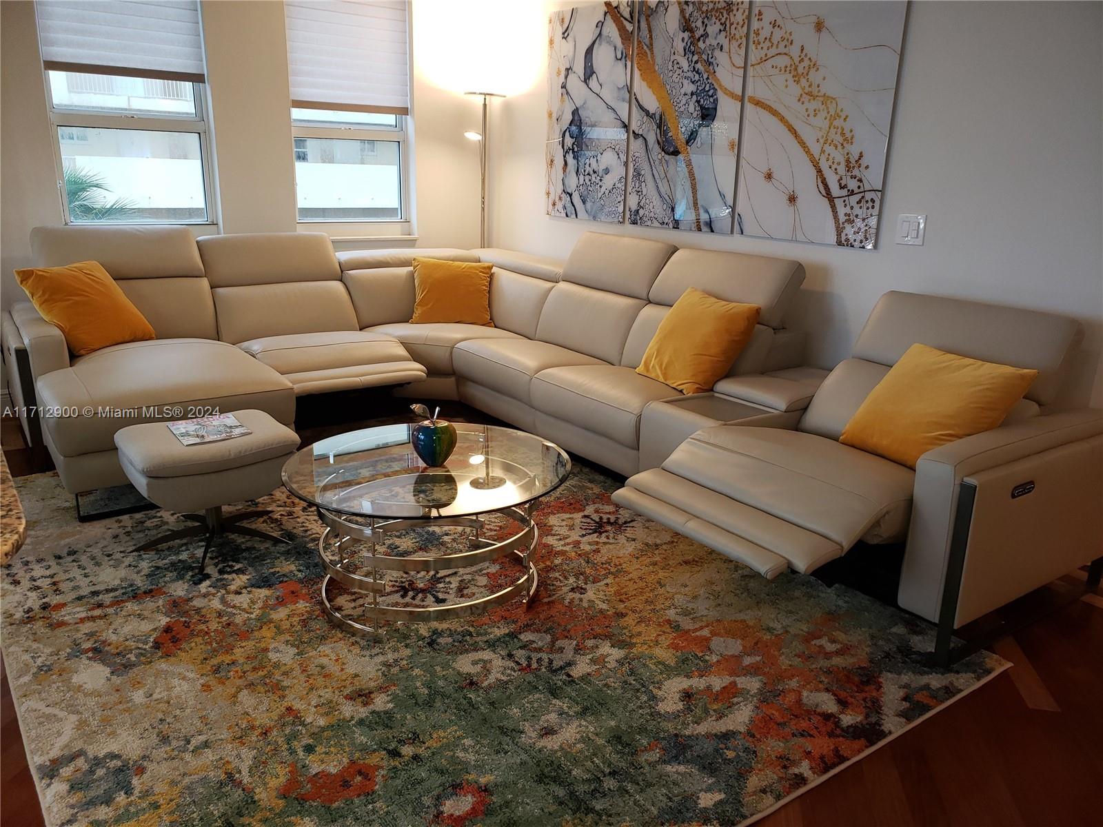 A living room features a large beige sectional sofa, a glass coffee table, and colorful rug — 2080 S Ocean Dr # 311, Hallandale Beach FL 33009, HALLANDALE BEACH, FL
