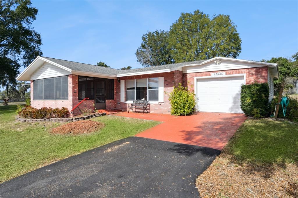 A single-story brick house features a screened-in porch, a one-car garage, and a paved driveway — 17530 COUNTY ROAD 455, MONTVERDE, FL
