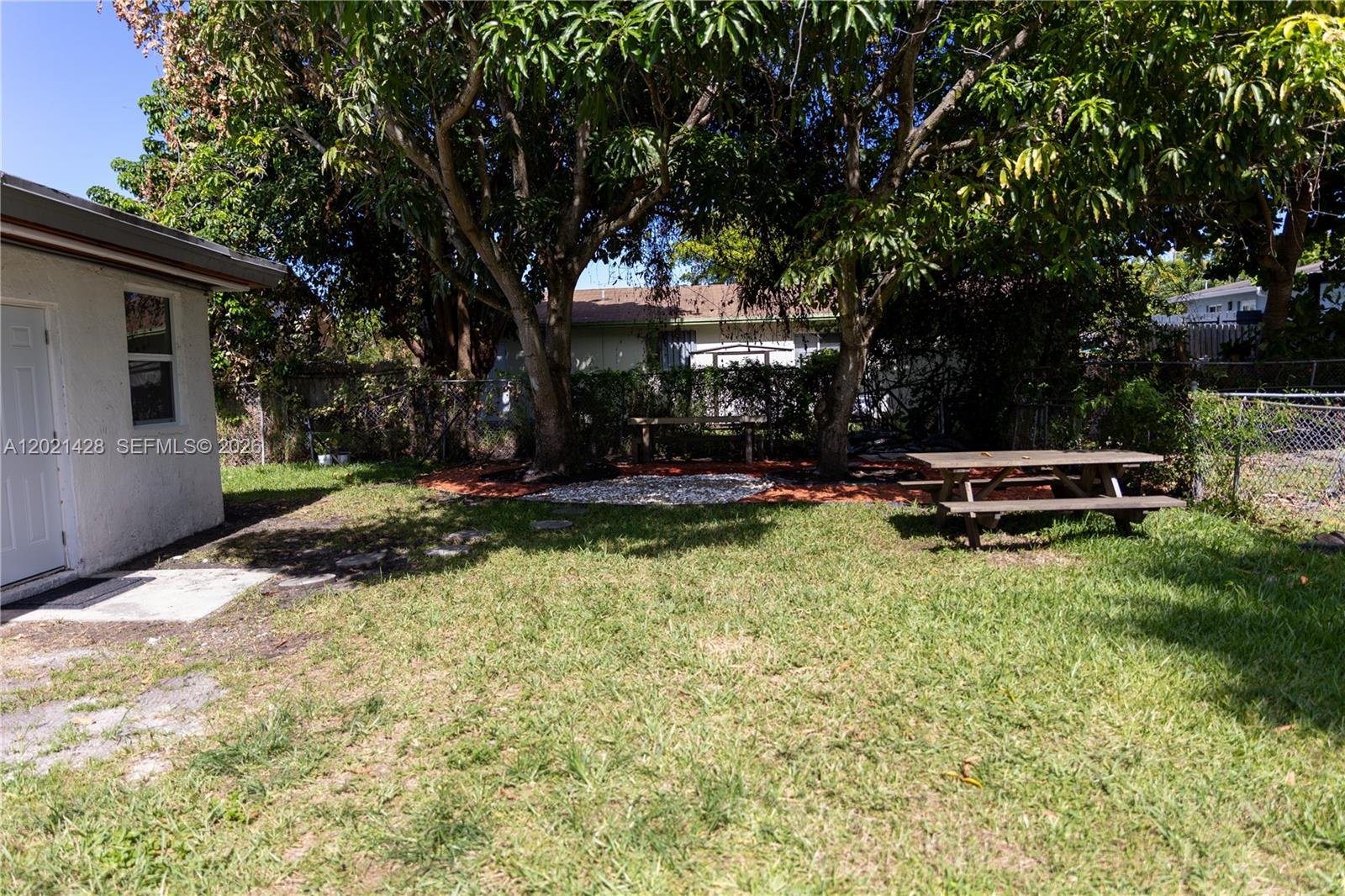 A backyard features a picnic table, mature trees, and a small white building — 250 NW 14th Way, Dania Beach FL 33004, DANIA BEACH, FL