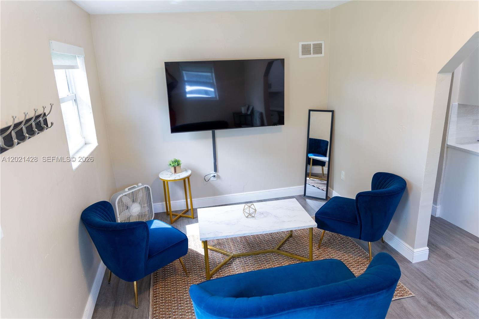 A living room features blue velvet chairs, a marble coffee table, and a wall-mounted television — 250 NW 14th Way, Dania Beach FL 33004, DANIA BEACH, FL