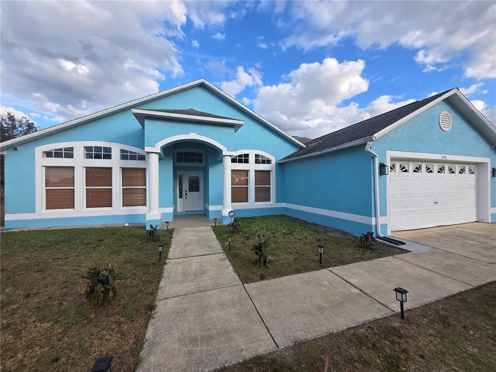 A bright blue single-story house with a white trim, arched entryway, and a two-car garage — 3190 LORI COURT, DELTONA, FL