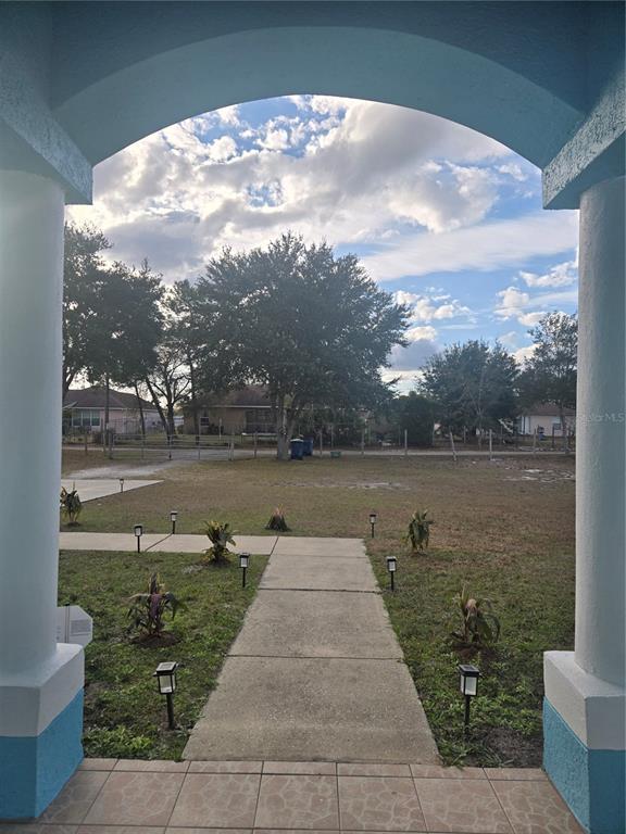 A view from a covered porch looking out over a concrete walkway and a grassy yard — 3190 LORI COURT, DELTONA, FL