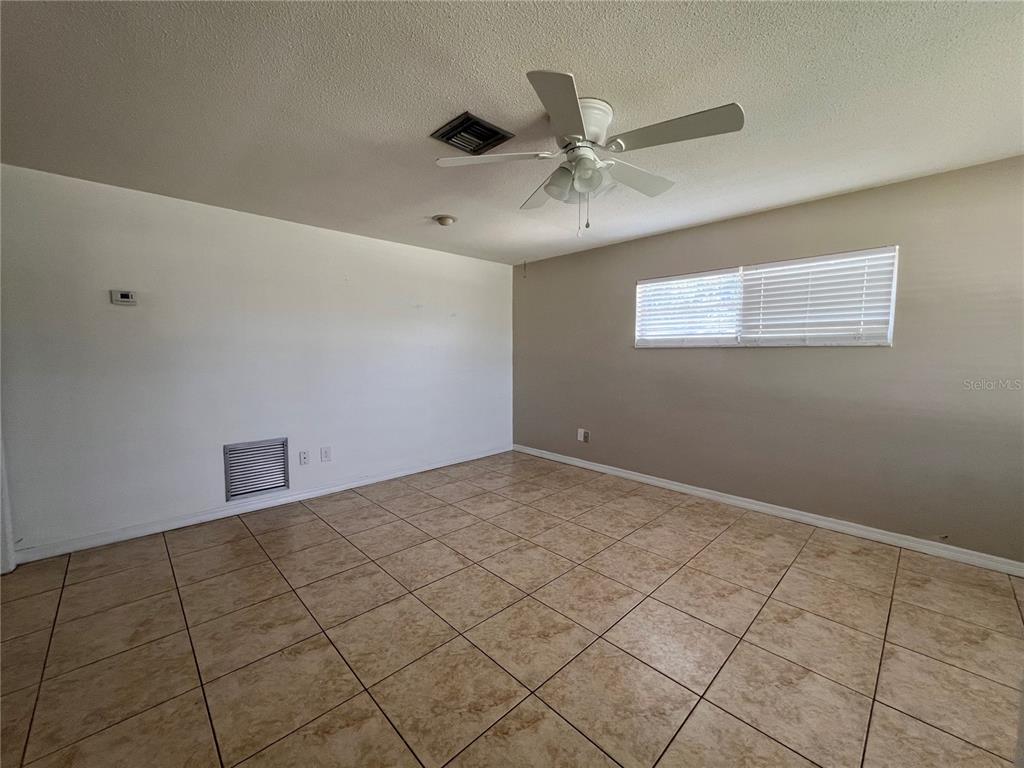 An empty room features beige tile flooring, a ceiling fan, and a window with blinds — 1238 WOODMERE DR, ALTAMONTE SPRINGS, FL