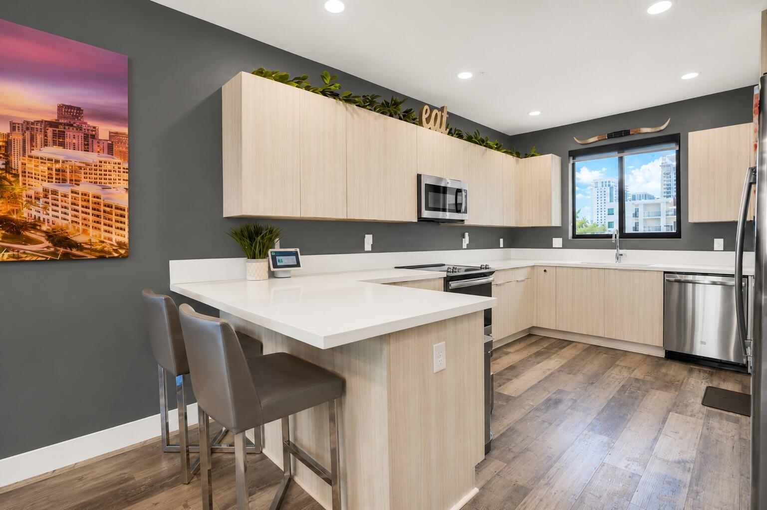A modern kitchen features light wood cabinets, white countertops, stainless steel appliances, and gray walls — 4716 NW 84th Court, Doral FL 33166, DORAL, FL