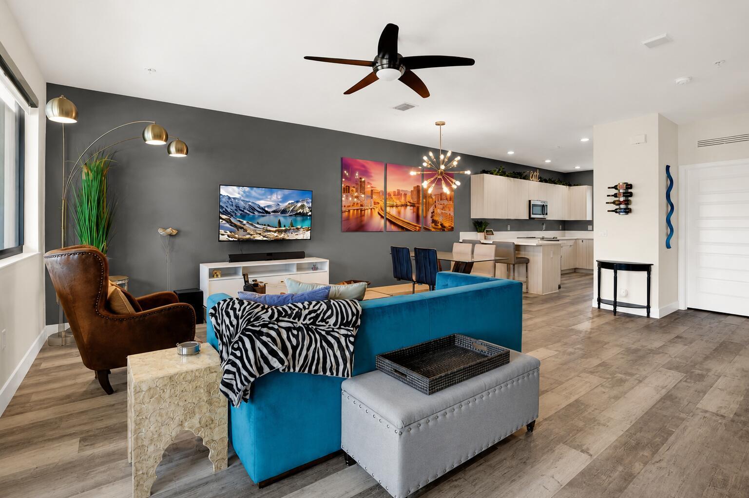 An open-concept living room and kitchen feature a blue sofa, gray walls, and wood flooring — 4716 NW 84th Court, Doral FL 33166, DORAL, FL