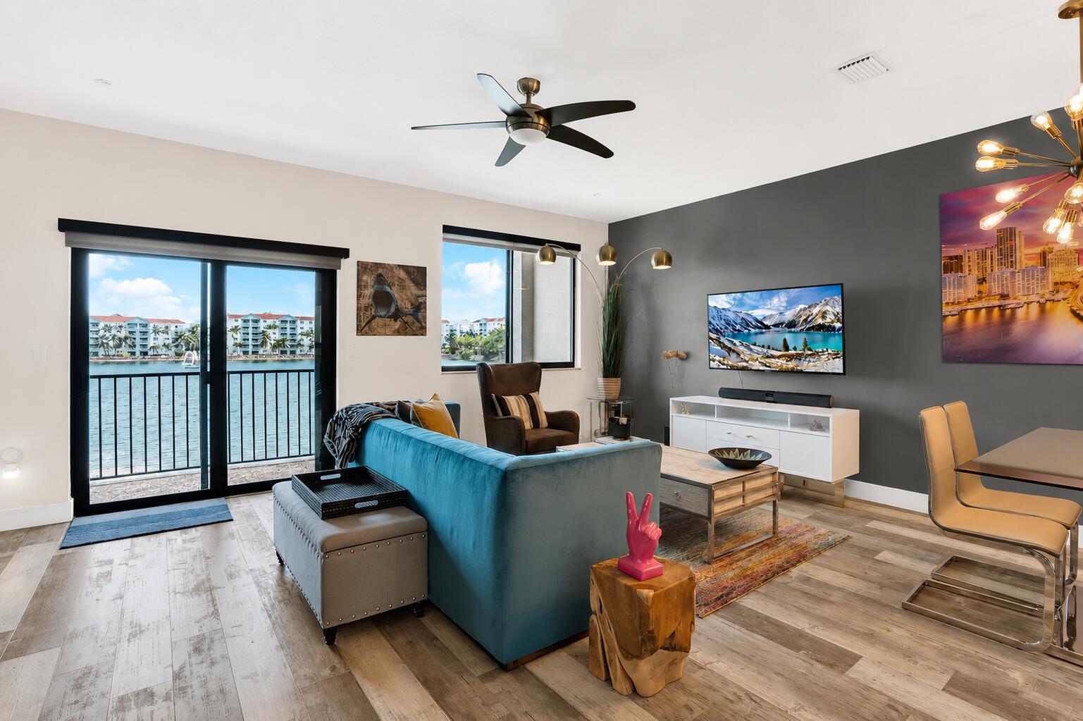 A living room features a blue sofa, gray ottoman, and a view of waterfront buildings — 4716 NW 84th Court, Doral FL 33166, DORAL, FL