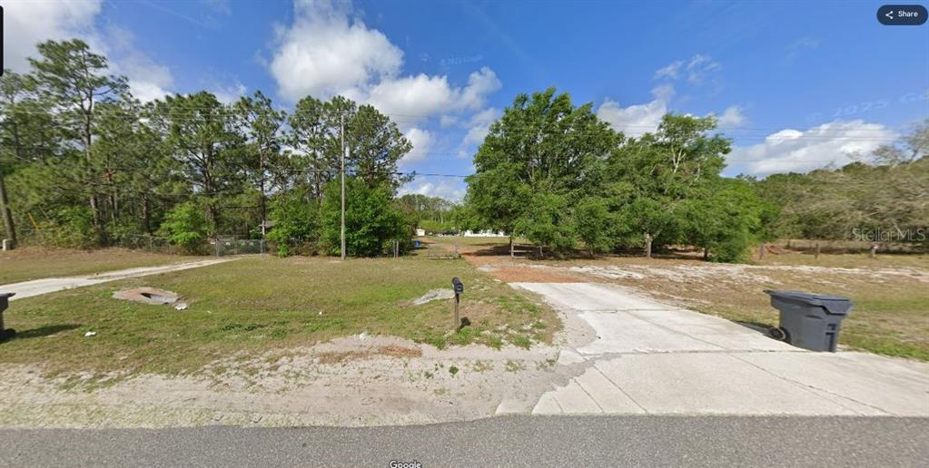 A gravel and concrete driveway leads to a wooded lot with a mailbox and trees — COMMONWEALTH AVENUE N, POLK CITY, FL