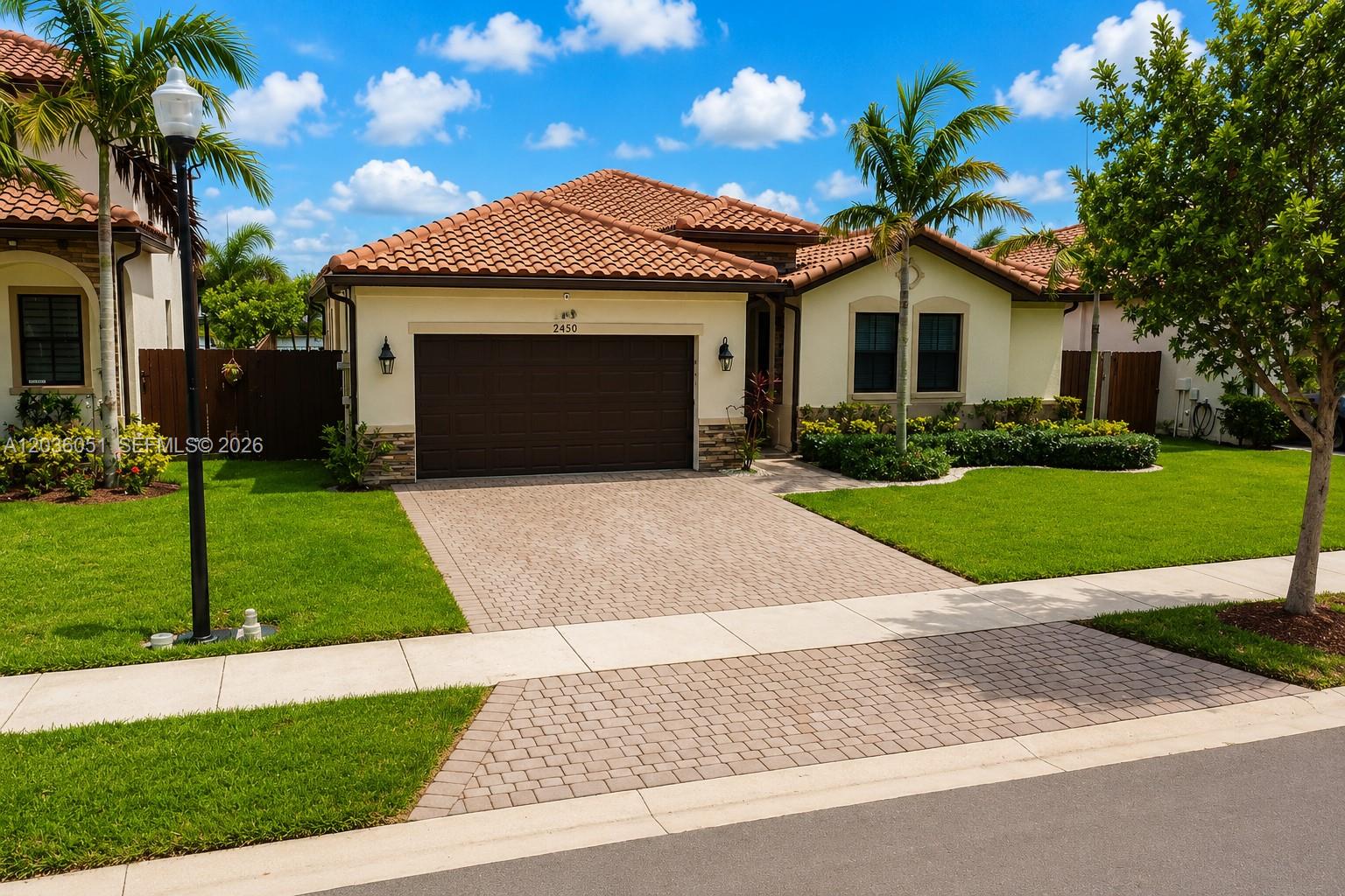 A single-story house with a tiled roof, a two-car garage, and a paved driveway — 2450 SE 1st St, Homestead FL 33033, HOMESTEAD, FL