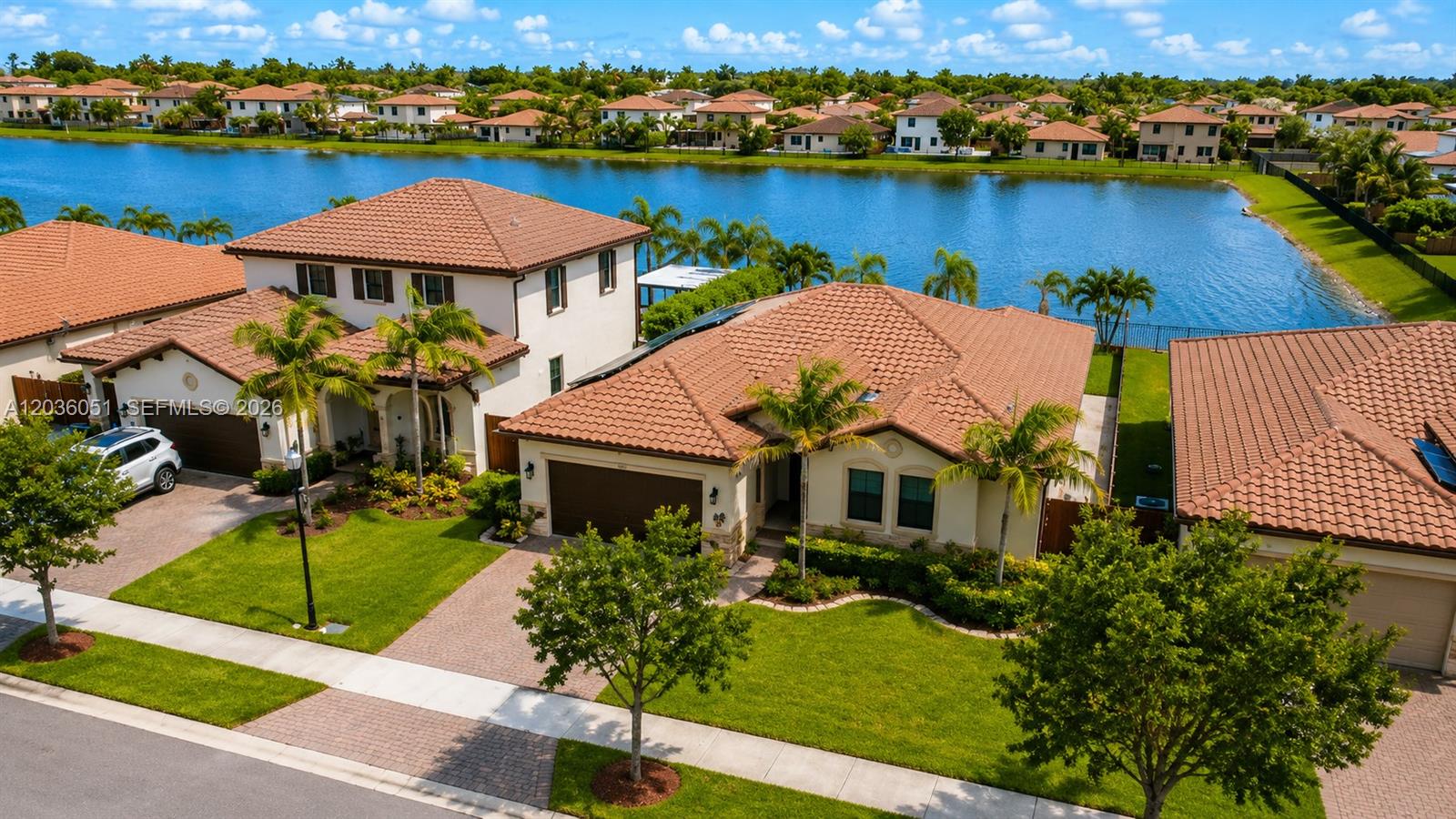 An aerial view shows two suburban houses with tiled roofs situated next to a lake — 2450 SE 1st St, Homestead FL 33033, HOMESTEAD, FL