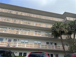 A low-angle exterior view of a multi-story apartment building with balconies and a palm tree — 5603 80TH STREET N UNIT 512, ST PETERSBURG, FL