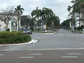 A view of the entrance to a residential community with palm trees and a sign — 5603 80TH STREET N UNIT 512, ST PETERSBURG, FL