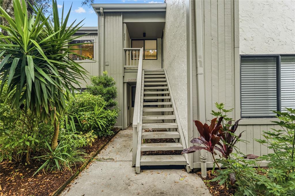 An exterior view of a multi-story building featuring a wooden staircase leading to an entrance — 1508 PELICAN COVE ROAD UNIT 235, SARASOTA, FL