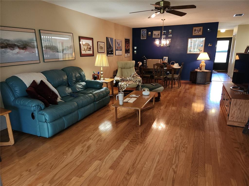 A living room features a blue sofa, hardwood floors, and a dining area with blue walls — 3439 TALLYWOOD LANE UNIT 7139, SARASOTA, FL