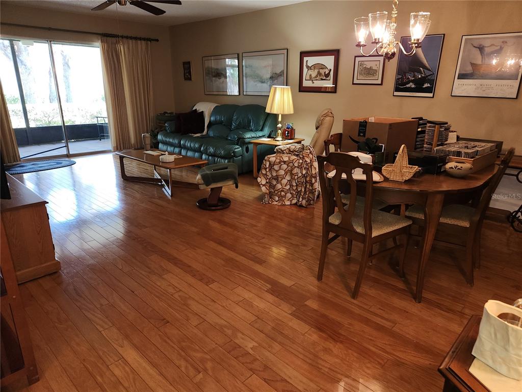 A living and dining area with hardwood floors, a green sofa, and a wooden table — 3439 TALLYWOOD LANE UNIT 7139, SARASOTA, FL