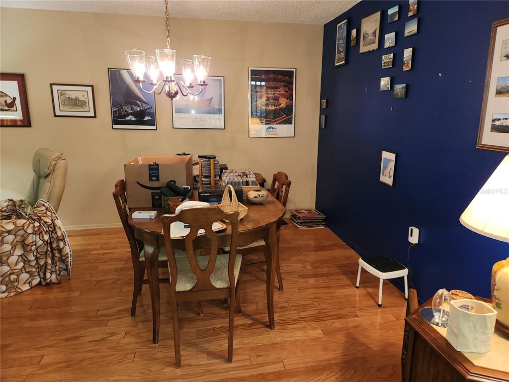 A dining room features hardwood floors, a wooden table with chairs, and blue accent walls — 3439 TALLYWOOD LANE UNIT 7139, SARASOTA, FL