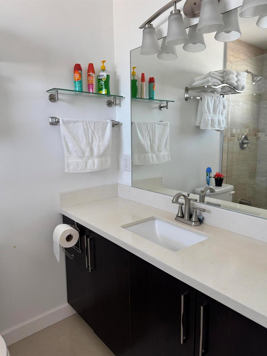 A tiled walk-in shower with a glass door and grab bar sits beside a toilet — 201 N Ocean Boulevard, Pompano Beach FL 33062, POMPANO BEACH, FL