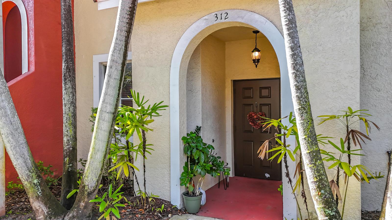 A brown front door with a heart wreath is centered under an arched entryway — 312 Bayfront Drive, Boynton Beach FL 33435, BOYNTON BEACH, FL