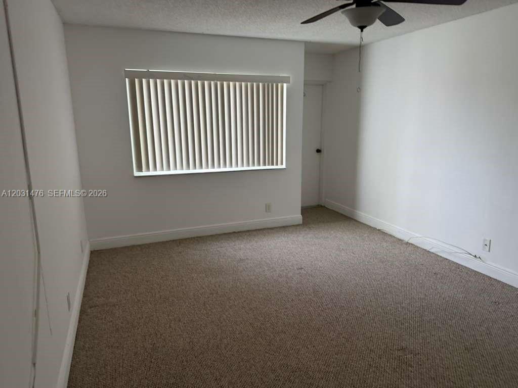 A bedroom features beige carpeting, white walls, a window with vertical blinds, and a ceiling fan — 140 Lakeview Dr # 211, Weston FL 33326, WESTON, FL