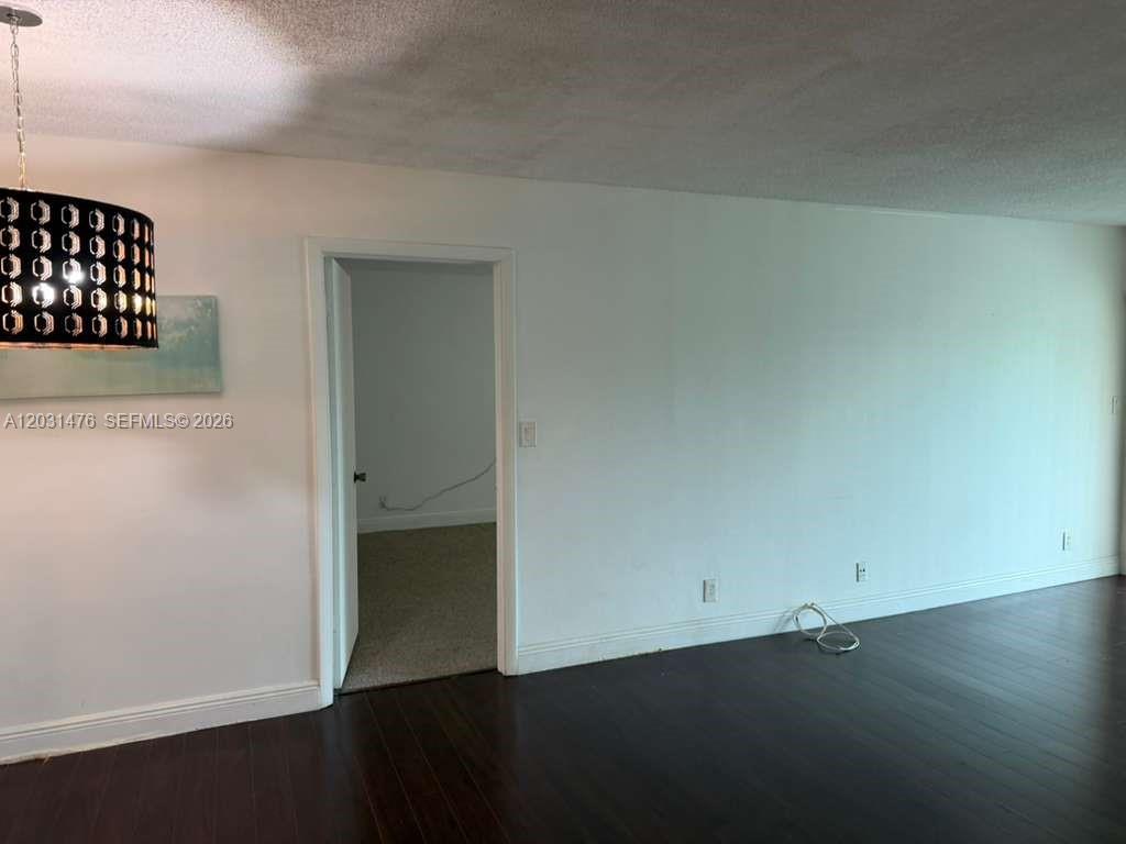 A room with dark wood flooring, white walls, and a patterned pendant light fixture — 140 Lakeview Dr # 211, Weston FL 33326, WESTON, FL