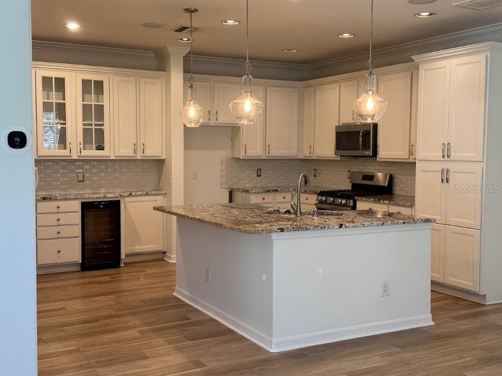 A kitchen features white cabinets, granite countertops, a central island, and stainless steel appliances — 11107 GREEN PARK CIRCLE, TAMPA, FL