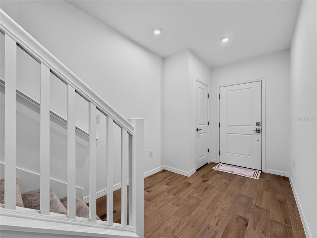 An entryway features wood-look tile flooring, a white staircase, and a front door — 3004 JESSAMINE DRIVE, TAVARES, FL
