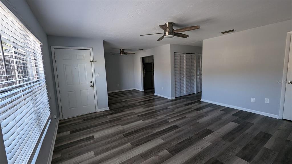 A living room with gray walls, wood-look flooring, a ceiling fan, and a white door — 3924 SW 26TH DRIVE UNIT 6, GAINESVILLE, FL