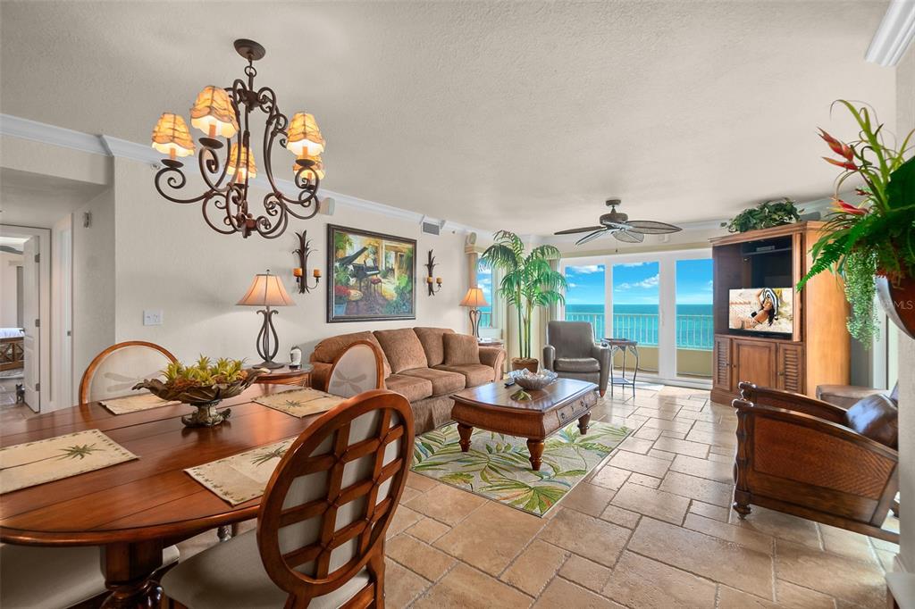 A living and dining area features tile floors, a chandelier, and a balcony with ocean views — 2937 S ATLANTIC AVENUE UNIT 1907, DAYTONA BEACH SHORES, FL