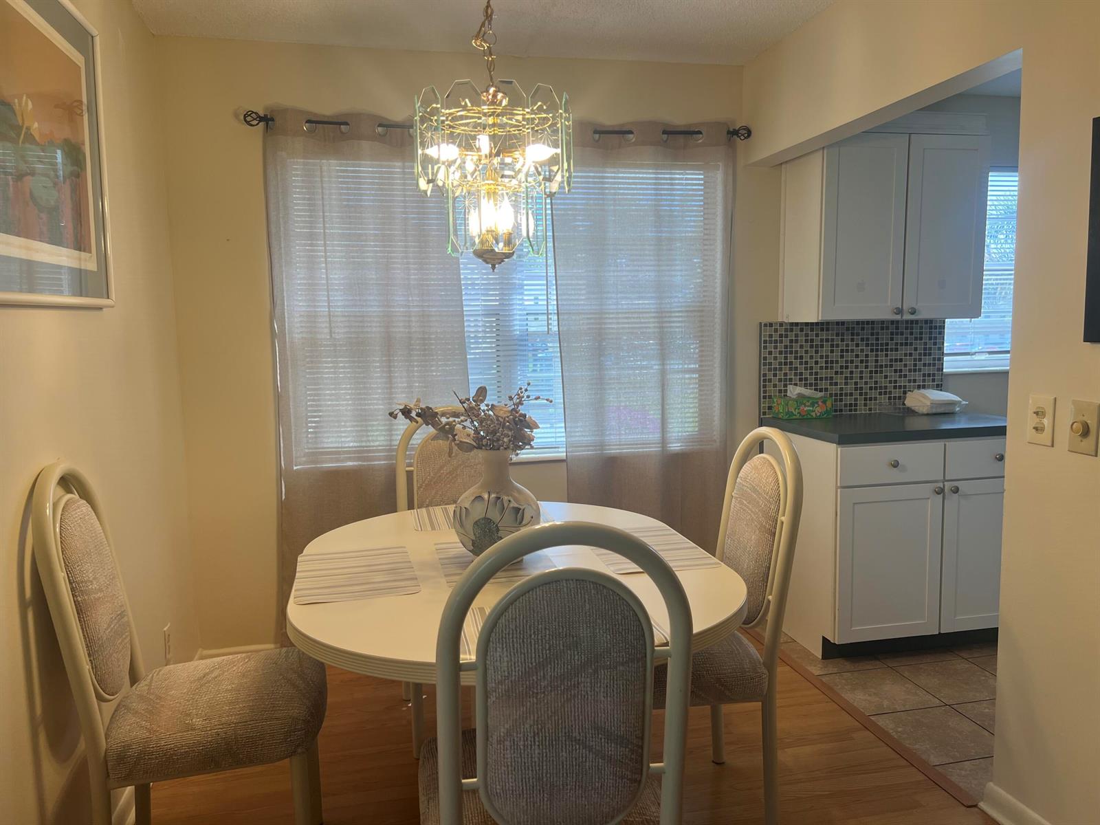 A dining area features a round white table, four chairs, and a crystal chandelier — 318 Mansfield H, Boca Raton FL 33434, BOCA RATON, FL