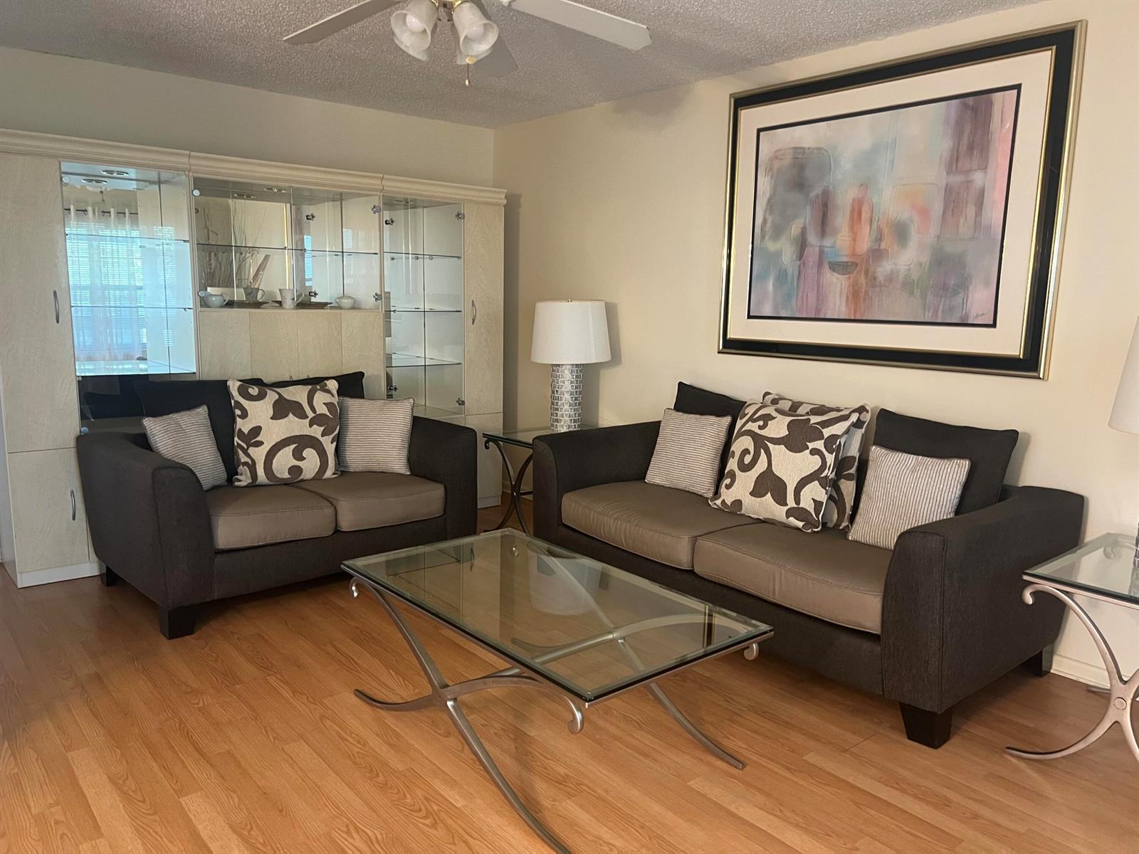 A living room features two dark sofas, a glass coffee table, and a large wall unit — 318 Mansfield H, Boca Raton FL 33434, BOCA RATON, FL