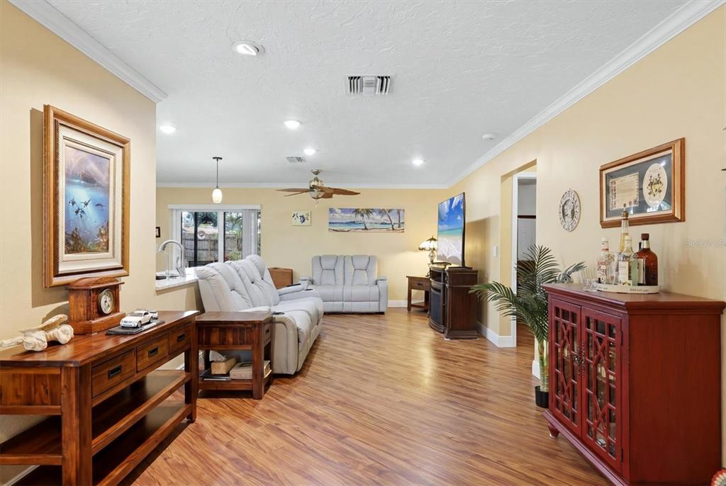 A living room features wood-look flooring, light yellow walls, a grey sofa, and a red cabinet — 918 ELL WAY, SARASOTA, FL