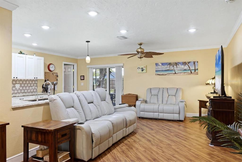 A living room with light-colored reclining sofas, wood-look flooring, and an open kitchen pass-through — 918 ELL WAY, SARASOTA, FL
