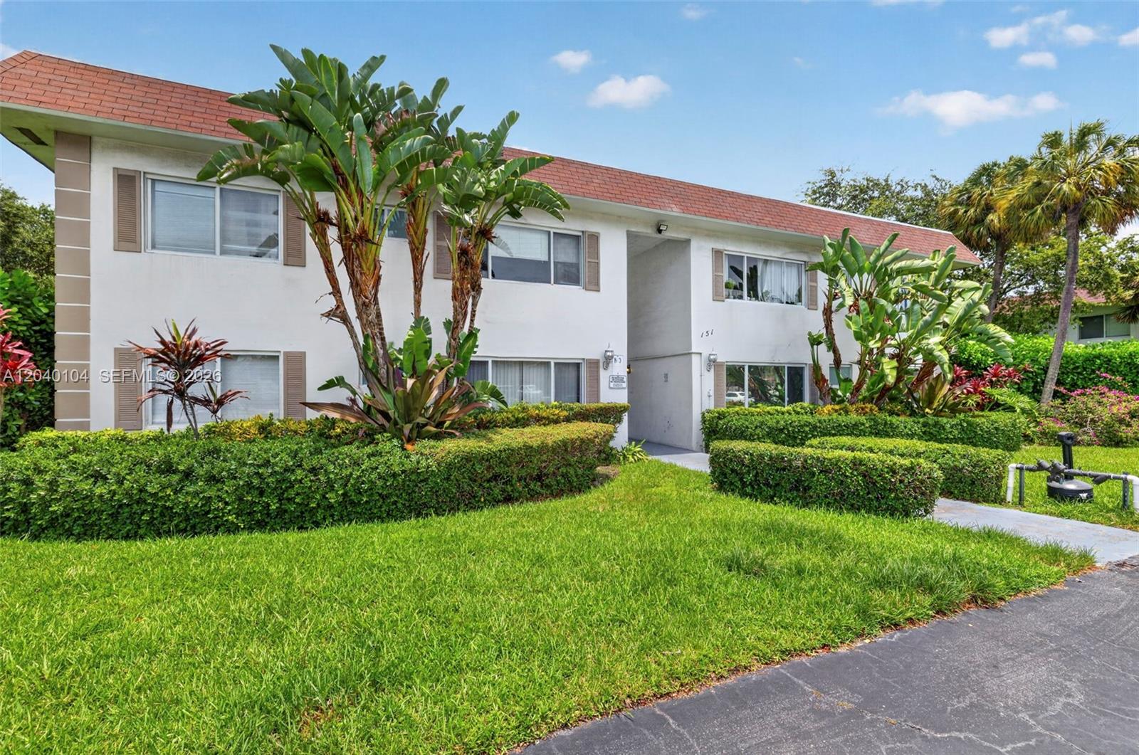 A two-story apartment building with white stucco walls, brown shutters, and manicured landscaping — 151 SE 6th Ave # 16, Pompano Beach FL 33060, POMPANO BEACH, FL