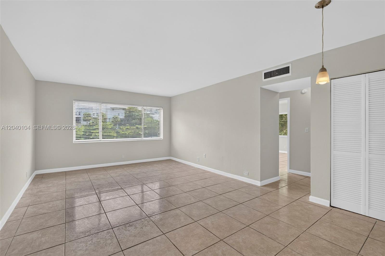 An empty room features beige tile flooring, light gray walls, and a large window — 151 SE 6th Ave # 16, Pompano Beach FL 33060, POMPANO BEACH, FL