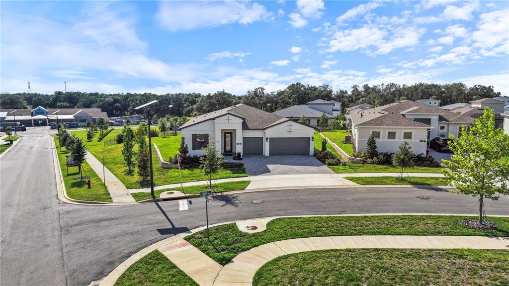 An aerial view shows a single-story suburban house with a paved driveway and green lawn — 442 TURIN WAY, LADY LAKE, FL
