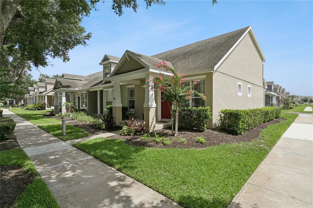 A beige townhouse with a covered front porch and a red door sits on a lawn — 13449 CARROWAY STREET, WINDERMERE, FL