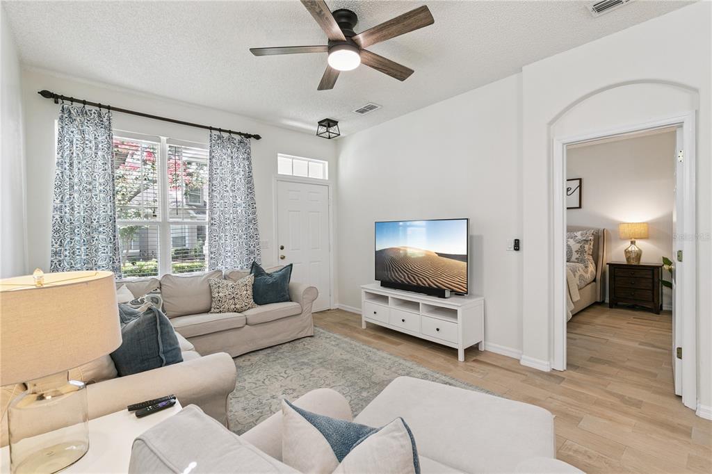A living room features a light-colored sofa, a television on a white stand, and hardwood floors — 13449 CARROWAY STREET, WINDERMERE, FL