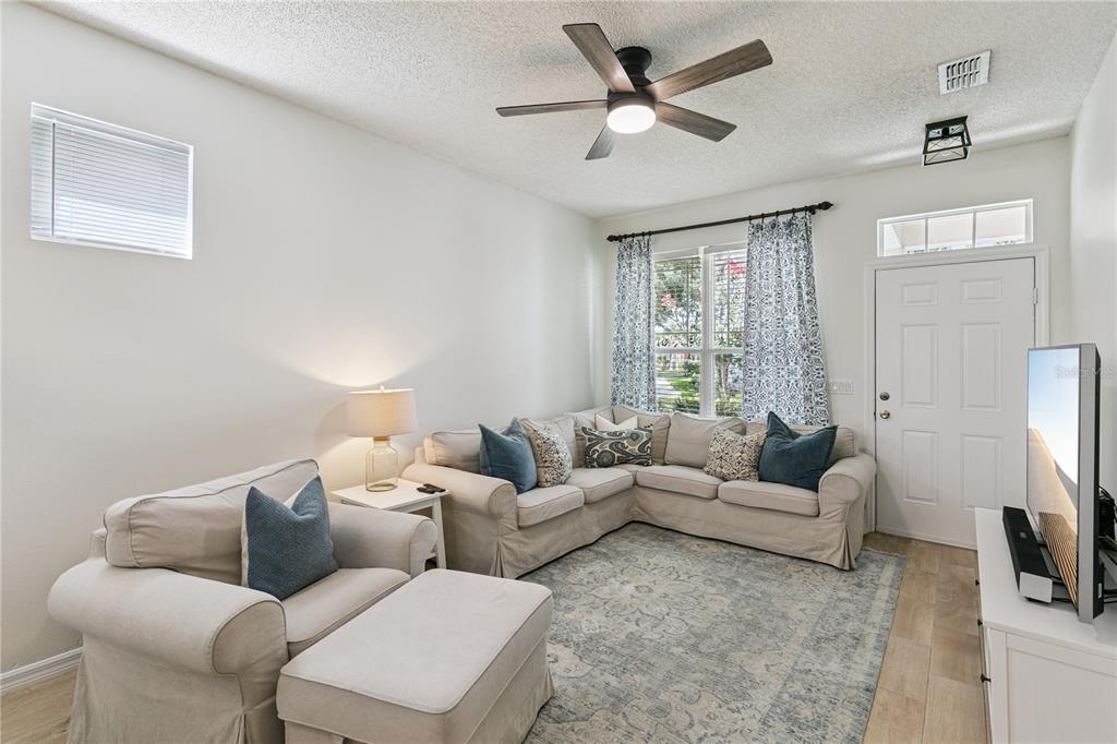 A living room features a beige sectional sofa, a matching armchair, and a ceiling fan — 13449 CARROWAY STREET, WINDERMERE, FL