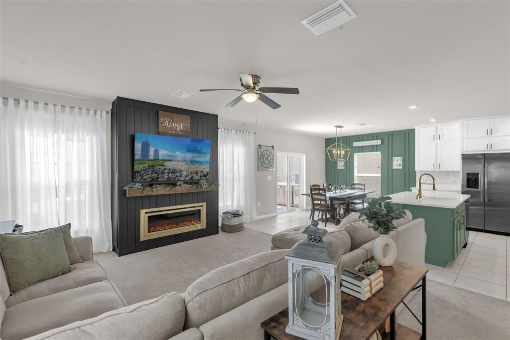 A living room and kitchen area feature a black fireplace wall and green cabinetry — 35179 BRIENNE STREET, ZEPHYRHILLS, FL