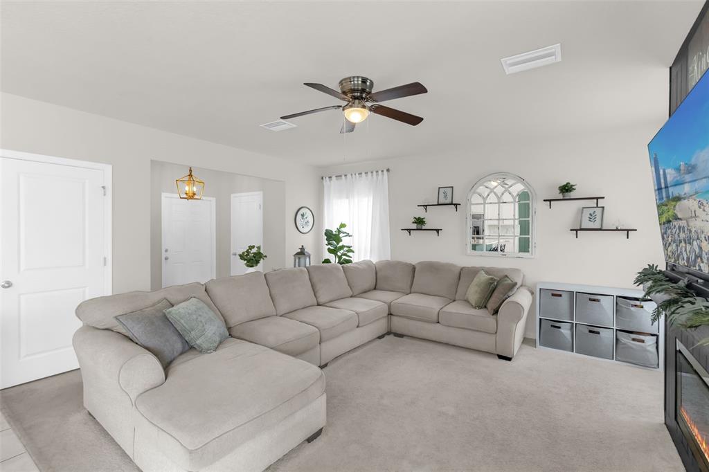 A living room features a large sectional sofa, a ceiling fan, and a wall-mounted television — 35179 BRIENNE STREET, ZEPHYRHILLS, FL
