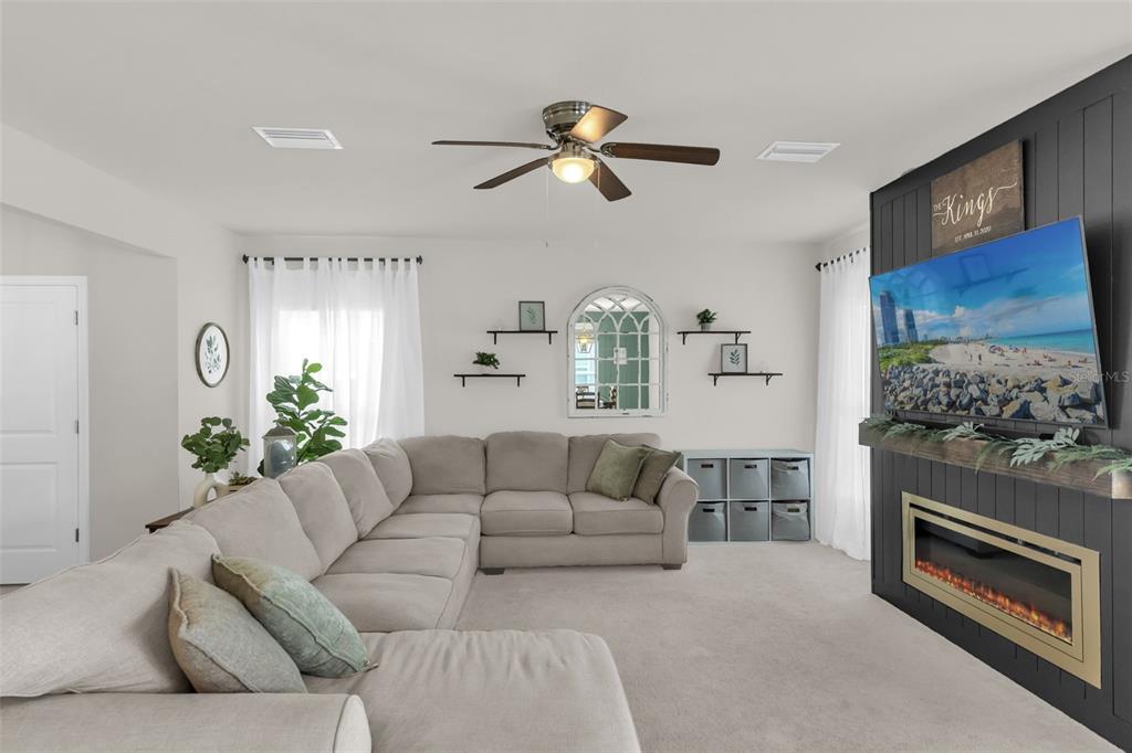 A living room features a large sectional sofa, a fireplace with a television, and shelving — 35179 BRIENNE STREET, ZEPHYRHILLS, FL