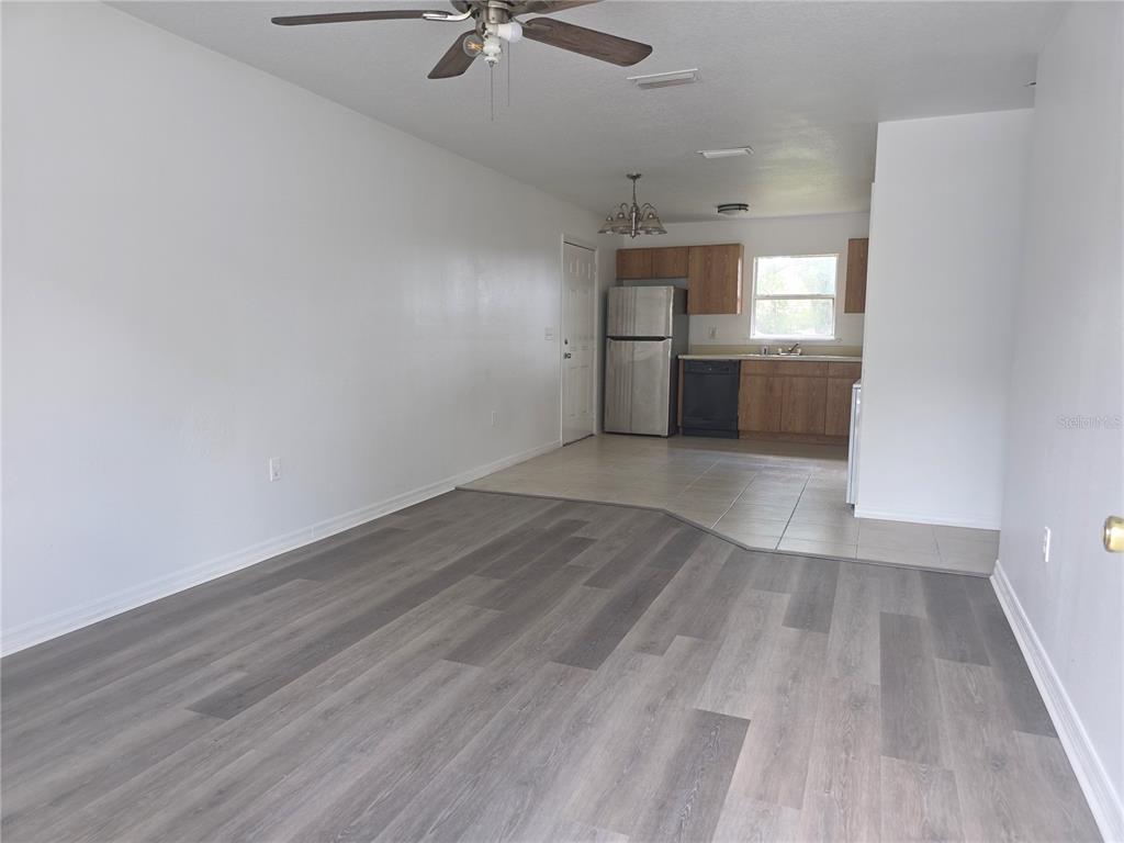 A living room with gray wood-look flooring transitions to a tiled kitchen with wood cabinets — 2017 N 61ST STREET, TAMPA, FL