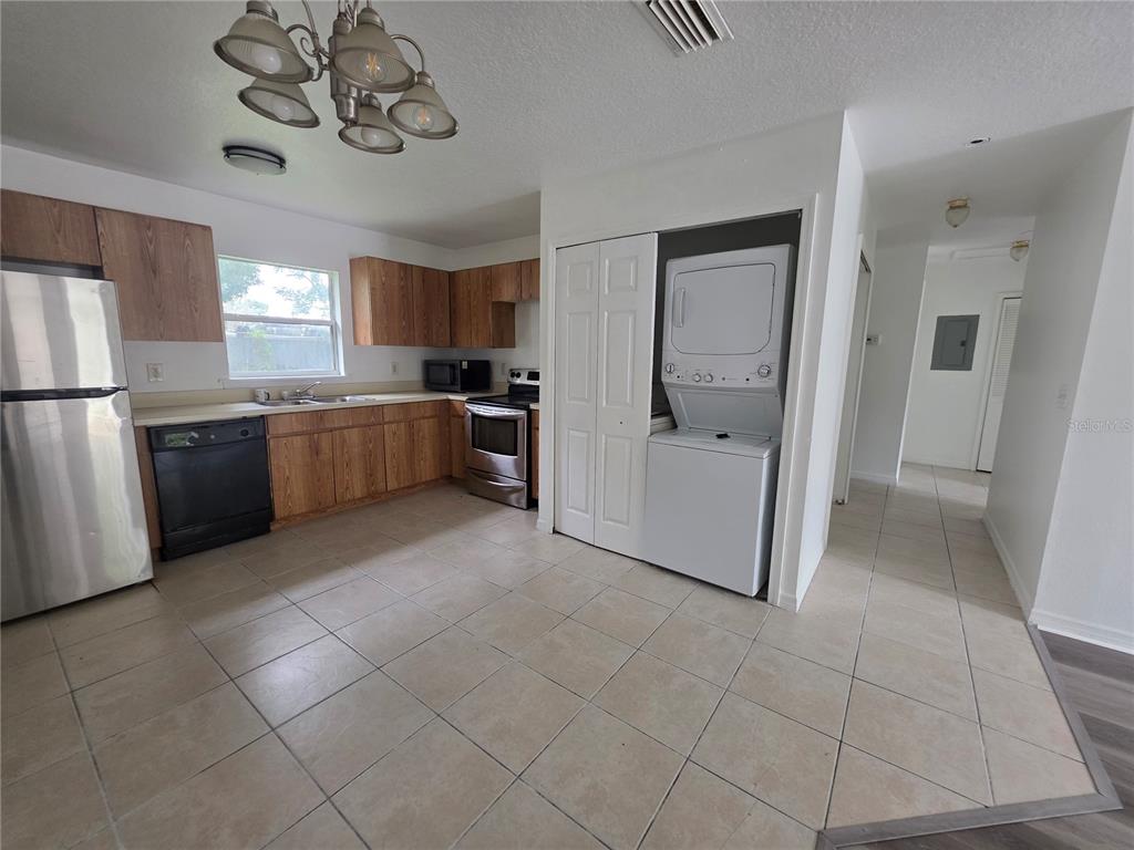 A kitchen features wood cabinets, stainless steel appliances, tile flooring, and a stacked laundry unit — 2017 N 61ST STREET, TAMPA, FL