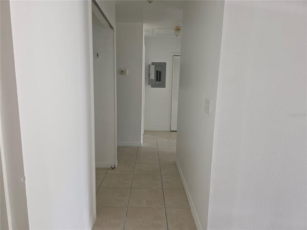 A hallway with light-colored tile flooring leads toward a circuit breaker panel and closet — 2017 N 61ST STREET, TAMPA, FL