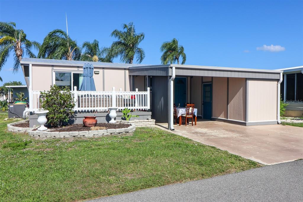 A single-story manufactured home with a white deck, carport, and landscaped front yard — 2100 KINGS HIGHWAY UNIT 662, PORT CHARLOTTE, FL