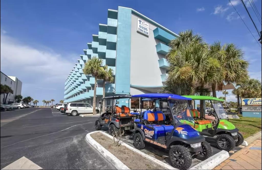 A multi-story hotel building with a parking lot and three golf carts in the foreground — 313 S ATLANTIC AVENUE UNIT 4100, DAYTONA BEACH, FL