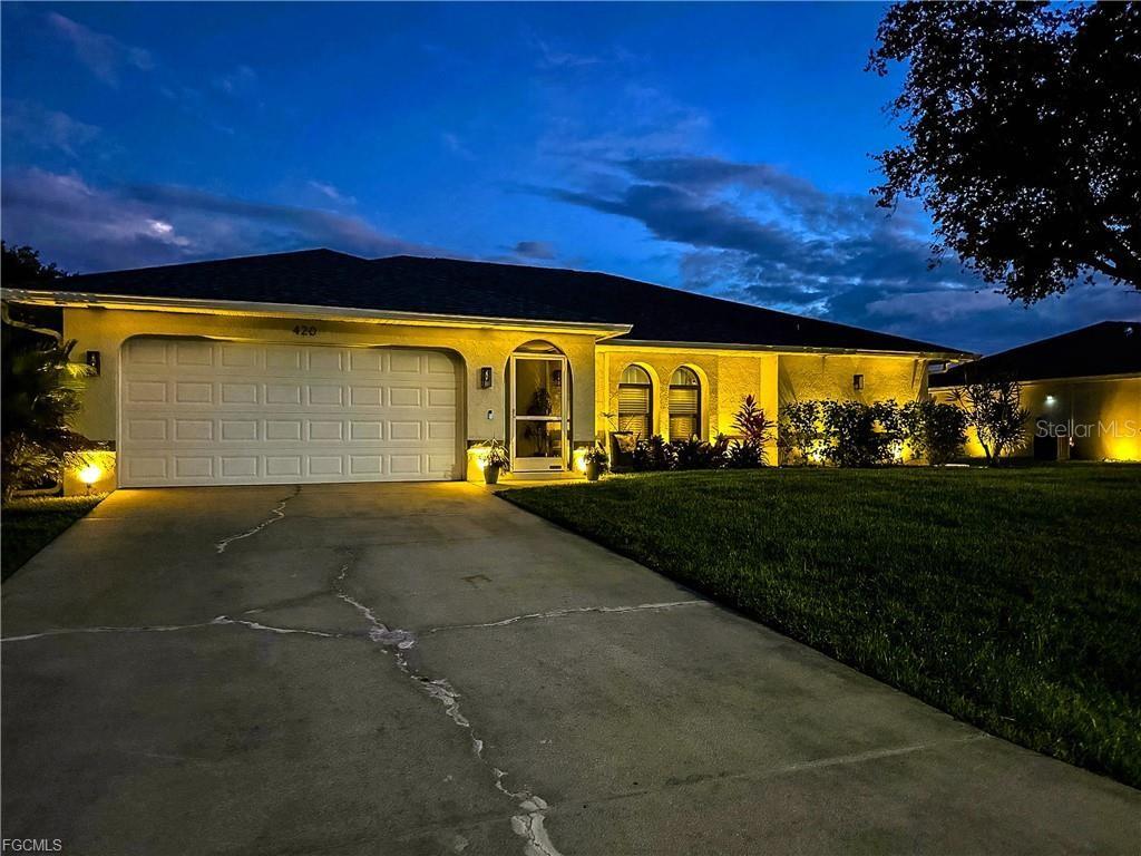 A single-story house with a two-car garage and a concrete driveway at dusk — 420 SW 37TH STREET, CAPE CORAL, FL