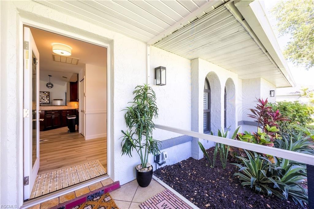 An open front door reveals a kitchen with wood cabinets and light-colored flooring — 420 SW 37TH STREET, CAPE CORAL, FL
