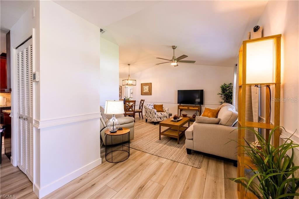 A living room with light wood flooring, a beige sofa, and a dining area beyond — 420 SW 37TH STREET, CAPE CORAL, FL