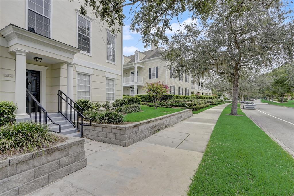 A multi-story light-colored building with a front porch and stairs sits beside a sidewalk — 236 CELEBRATION BOULEVARD UNIT 236, CELEBRATION, FL